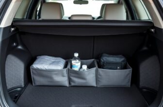 Organiseur de coffre gris rempli d'une couverture, d'une bouteille et d'une trousse dans un coffre de voiture