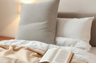 Grand coussin de lecture gris posé contre la tête d'un lit, avec un livre ouvert sur la couette