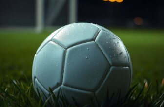 Ballon de football blanc posé sur une pelouse humide, de nuit, sous la lumière des projecteurs