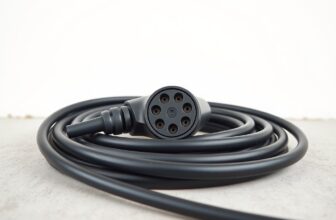 Câble de recharge noir enroulé sur un sol en béton, prise type 2 au premier plan