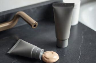 Tube de crème teintée sans étiquette et noisette de crème couleur chair sur une vasque gris anthracite