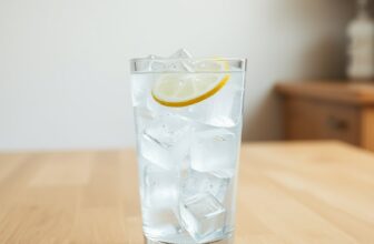 Verre d'eau pétillante rempli de glaçons transparents, avec une rondelle de citron, posé sur une table en bois clair